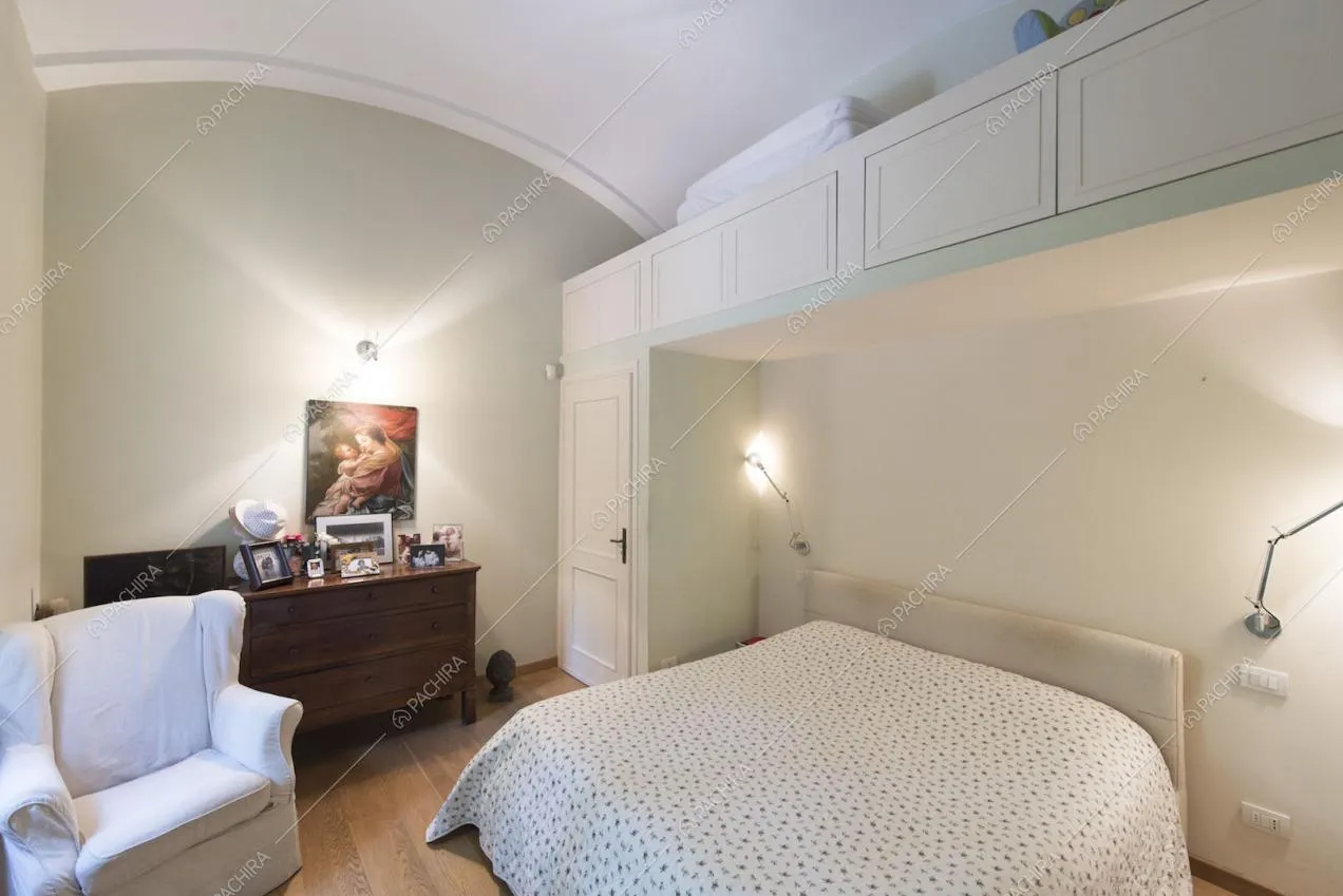 Camera da letto con poltrona bianca e soffitto a volta