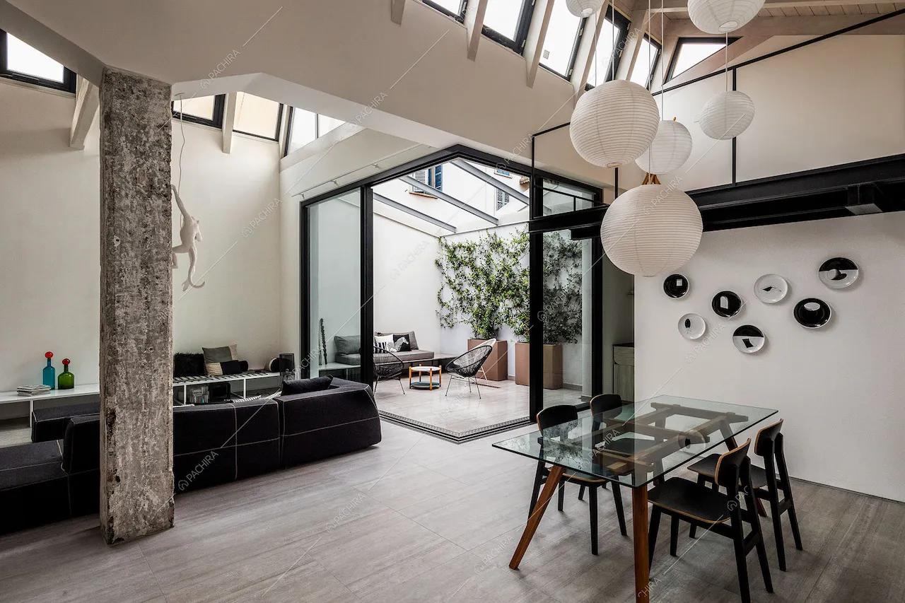Sala con tavolo da pranzo con piano in vetro, lampadario bianco di design e giardino d'inverno