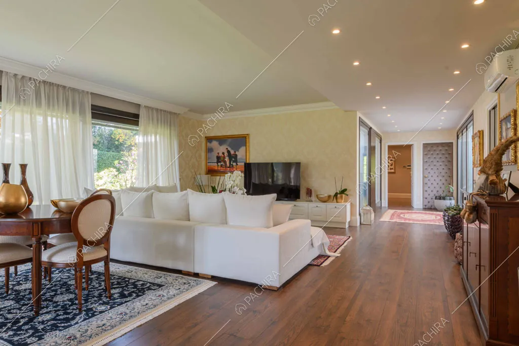 Carta da parati gialla nella zona living con pavimento in parquet e grandi vetrate