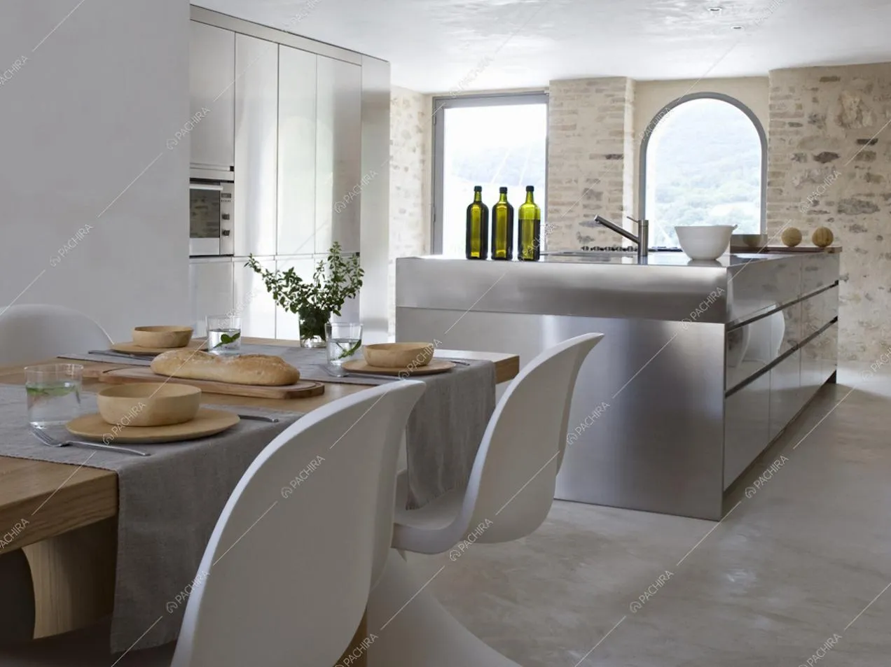 Il tavolo e la cucina a vista con dietro ampie vetrate