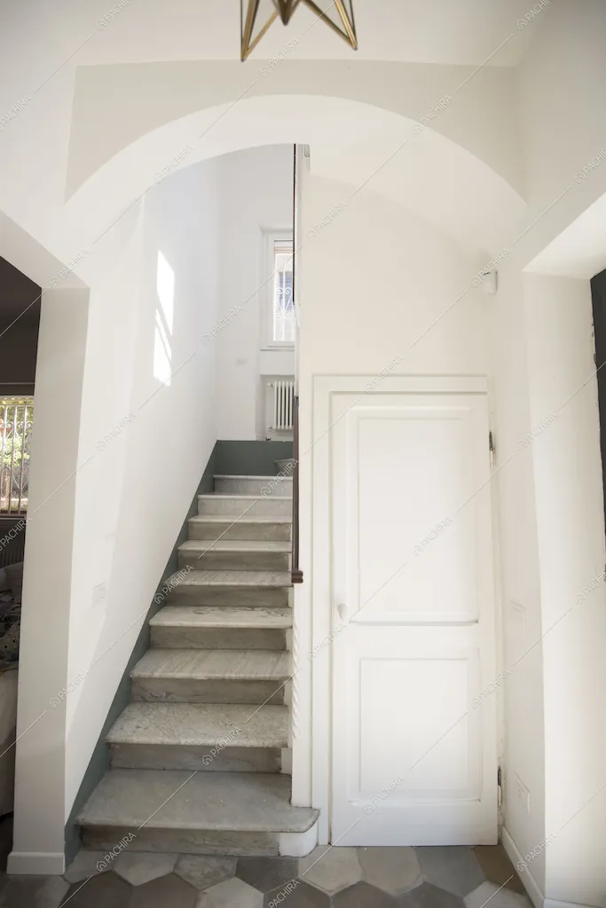 Scale in marmo, pavimento in cementine e porta bianca del bagno
