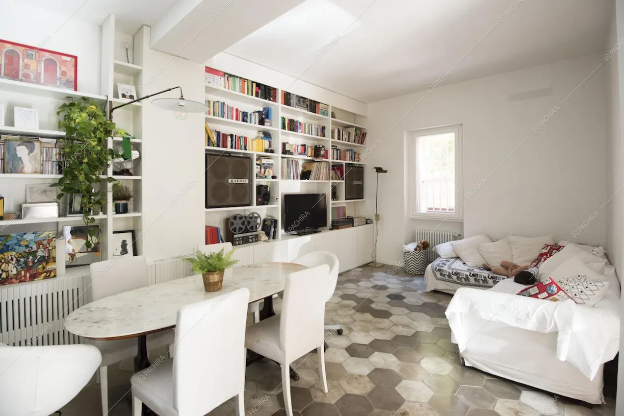Zona living con divano bianco, televisore e pavimento in cementine