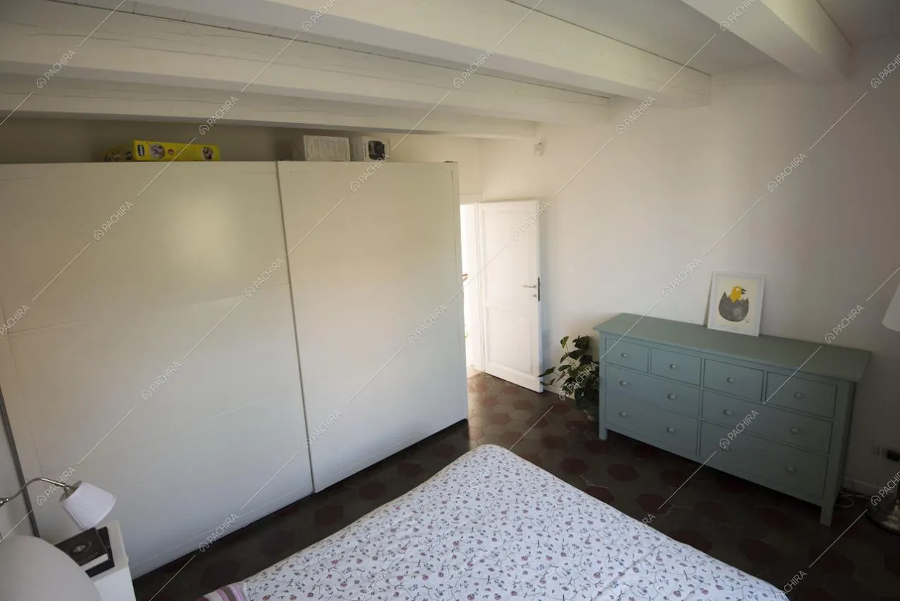 Camera da letto con grande cassettiera e travi bianche a vista