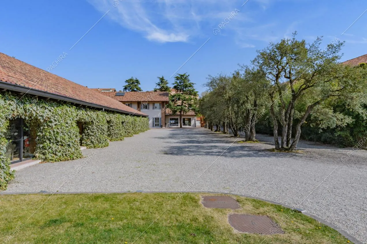 Grande cortile con aiuole, alberi e vista sugli esterni della location con rampicanti