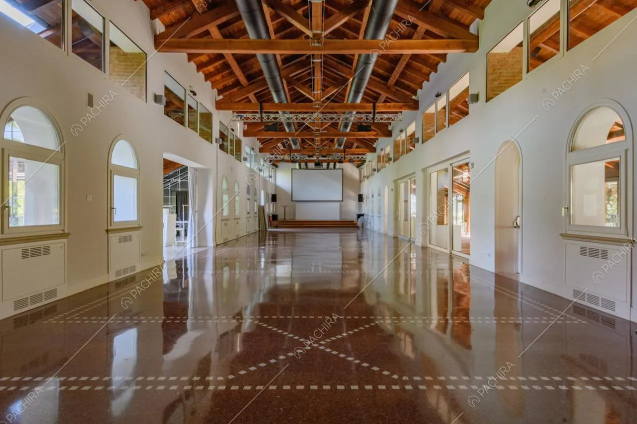 Travi in legno a vista sul soffitto, vetrate e pavimento in graniglia