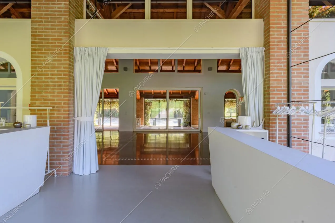 Dalla veranda vista sul grande salone con vetrate e colonne in mattoncini rossi