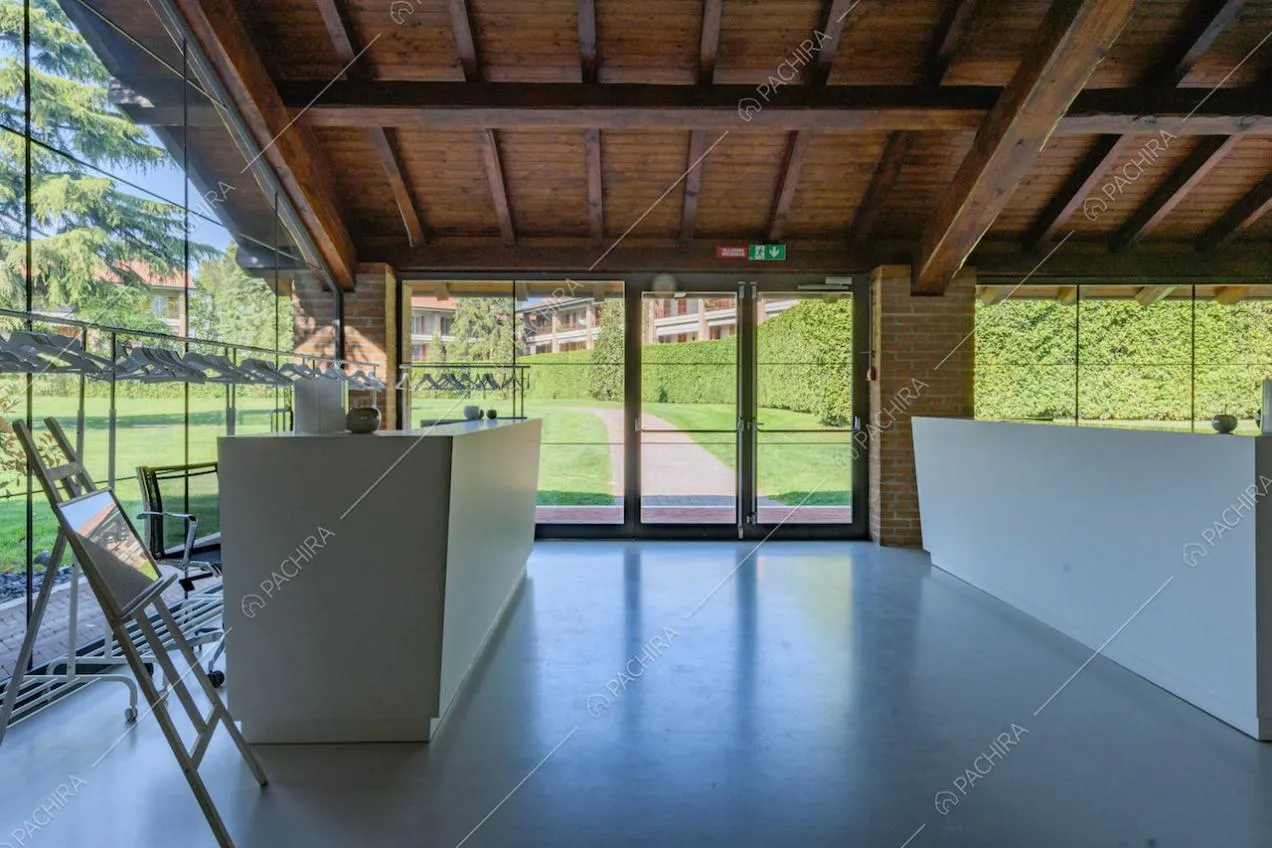 Vetrate e vista sul giardino nella veranda con travi in legno sul soffitto
