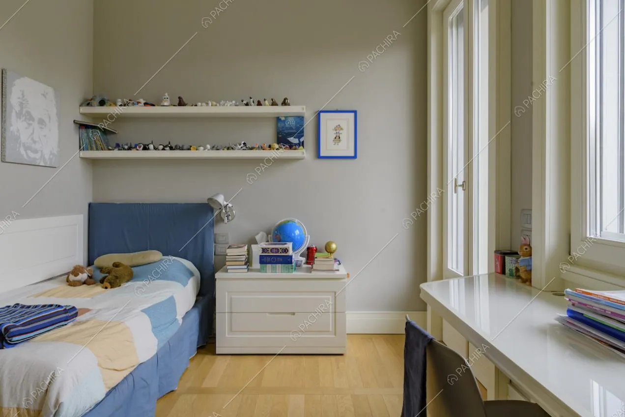 Camera con letto singolo, pareti grigie, pavimento in parquet e scrivania bianca
