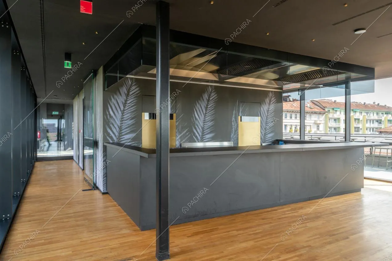 Bancone nero della location nell'ampio salone con pavimento in parquet e carta da parati