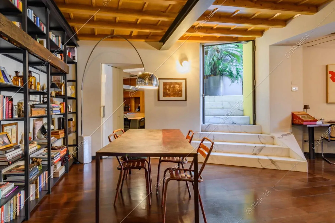 Nella sala da pranzo con tavolo in legno, libreria e gradini in marmo per accedere alla terrazza