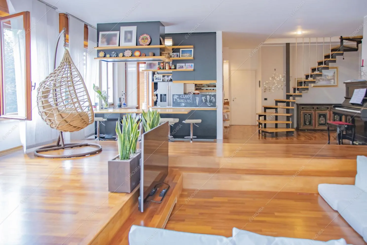 Luminoso salone con pavimento in parquet, cucina a vista e scale