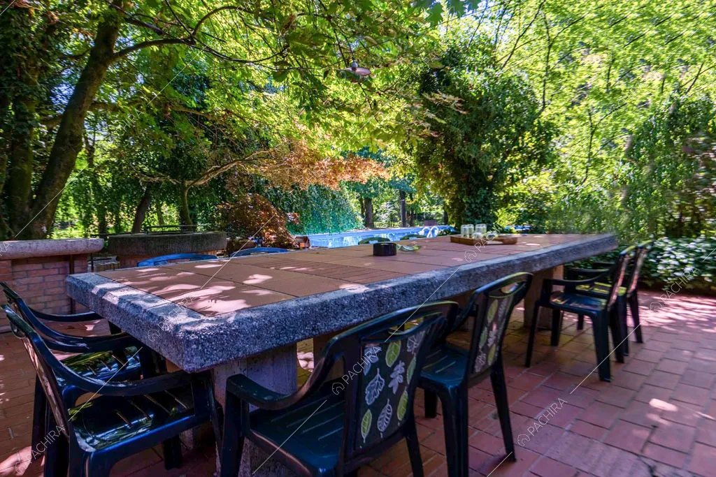 Grande tavolo da pranzo da esterni in pietra e sedie in plastica verde