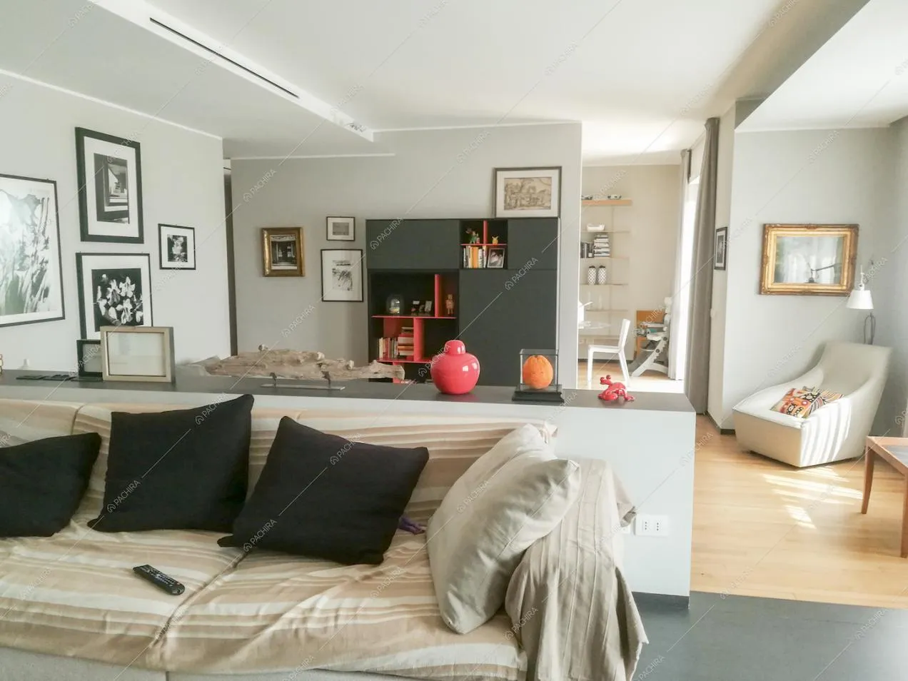 Divano nella zona living rialzata, scorcio sulla cucina e libreria nera