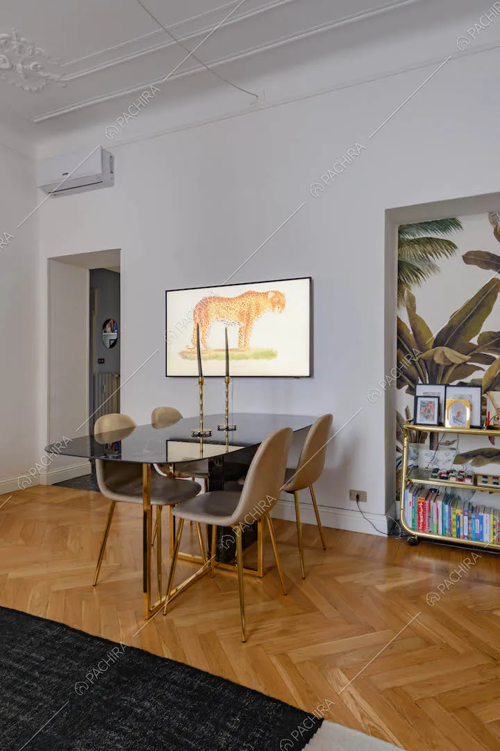 Tavolo da pranzo di design nel grande salotto con boiserie sul soffitto e carta da parati