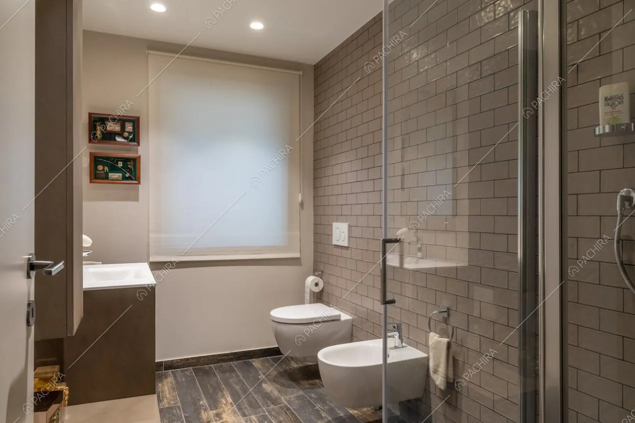 Bagno con pavimento in parquet, pareti in mattonelle e box doccia