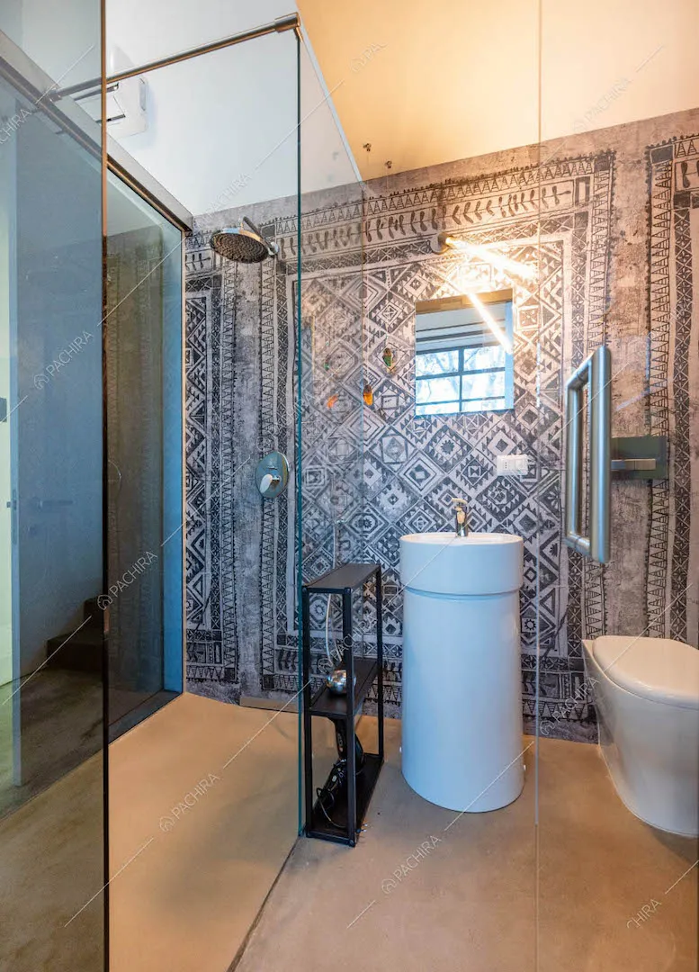 Bagno con carta da parati, box doccia e pavimento grigio in resina