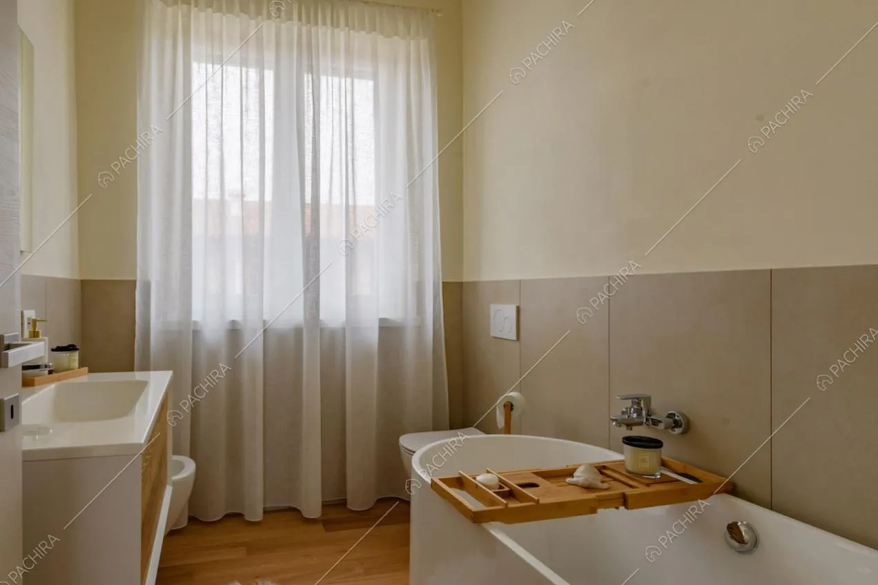 Luminoso bagno con pavimento in parquet, vasca e pareti gialle