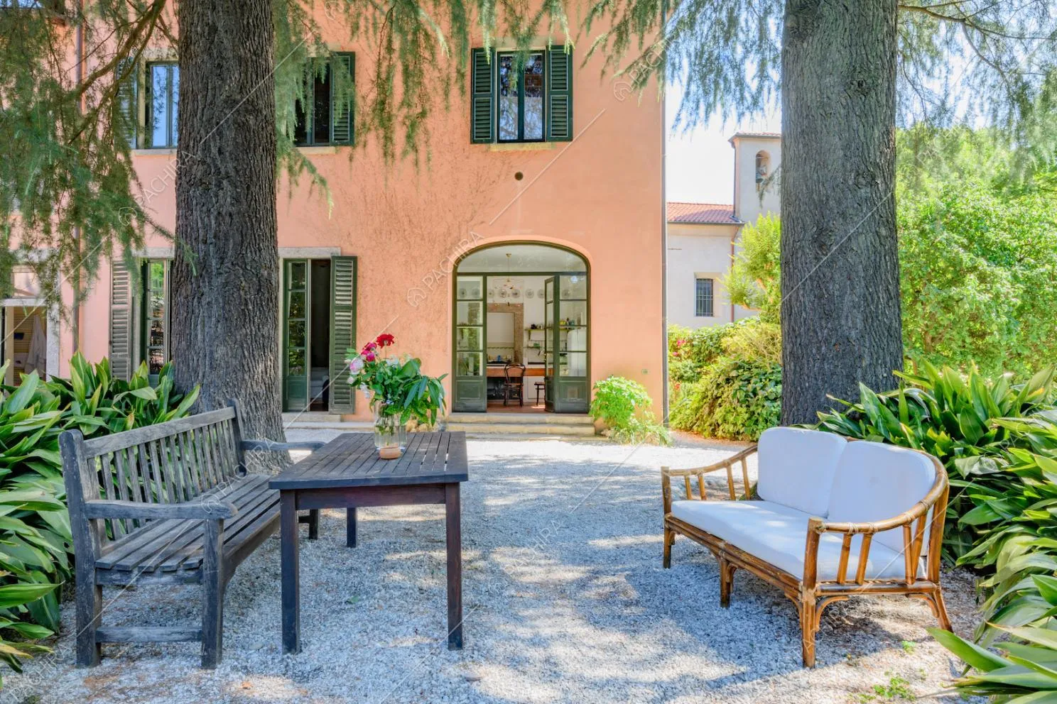 Panchine e tavolino nel giardino con vista sugli esterni rosa della location