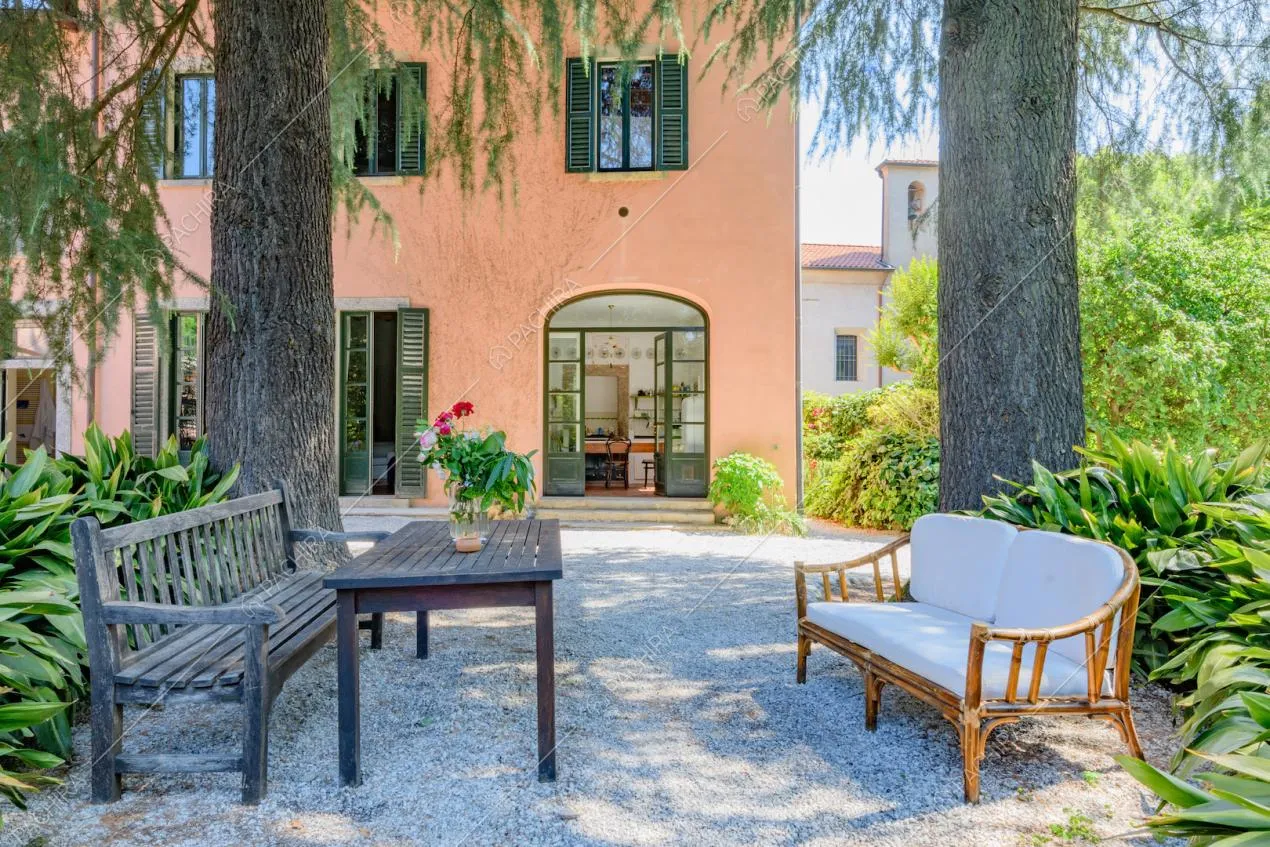 Panchine e tavolino nel giardino con vista sugli esterni rosa della location