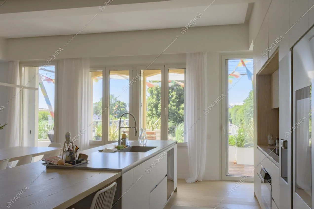Cucina con mobili dai colori tenui e grandi finestre