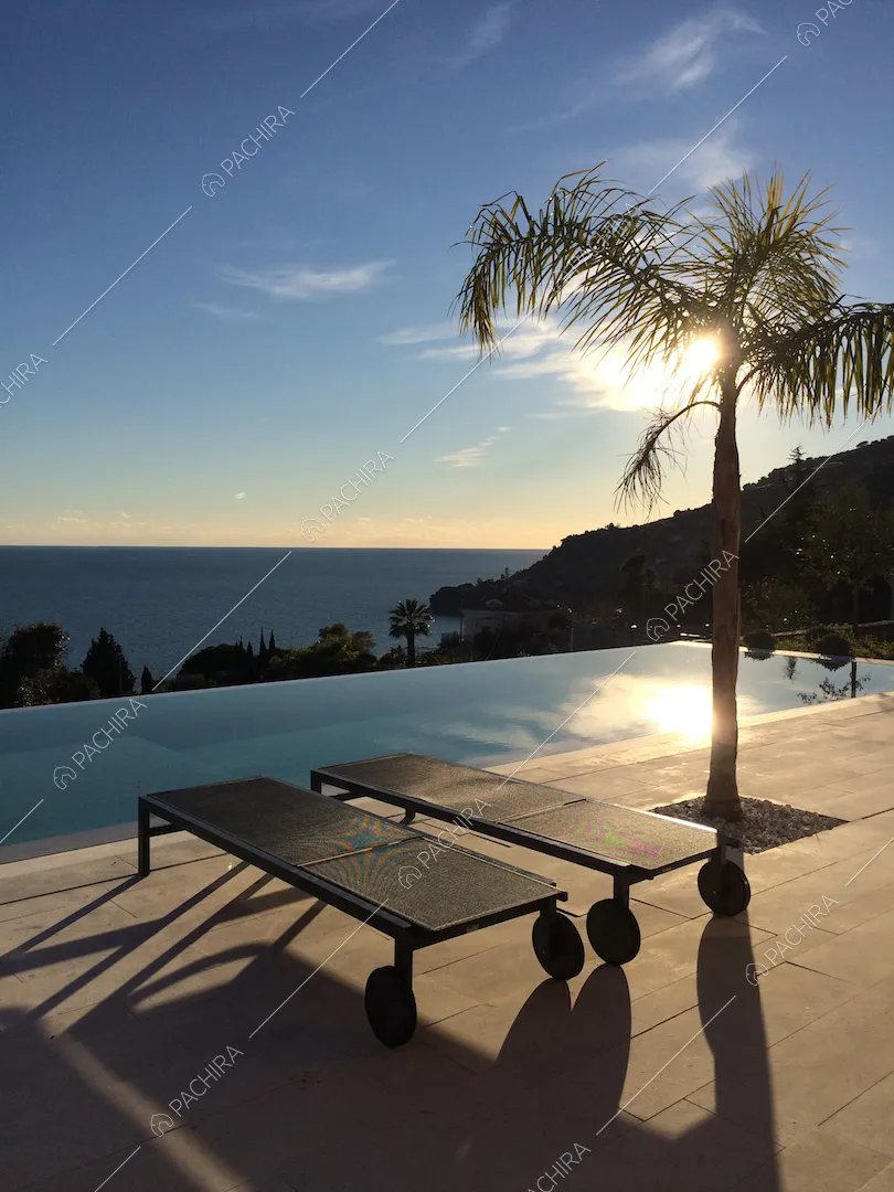 Lettini neri e palma sulla splendida terrazza con piscina vista mare