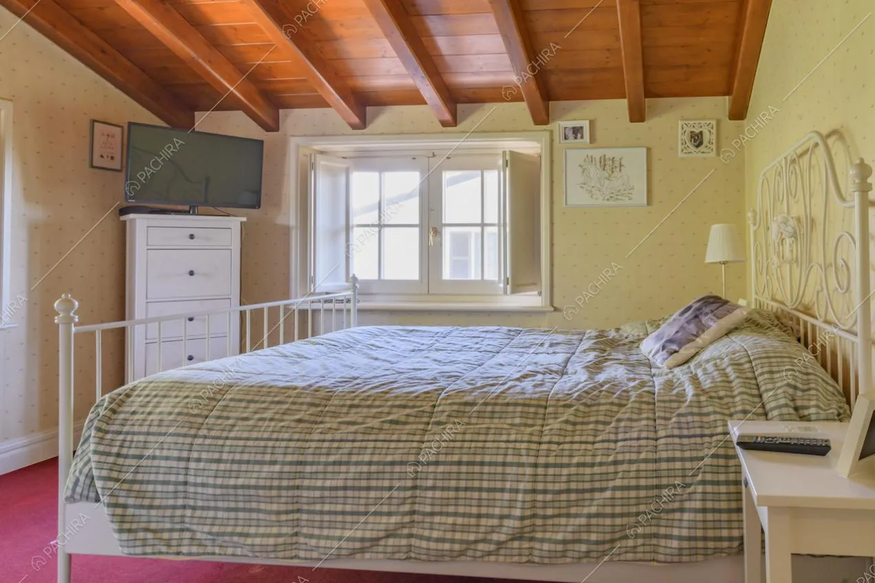 Letto matrimoniale con testiera decorata e travi a vista