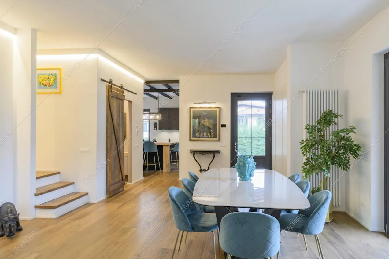 Zona pranzo con tavolo bianco e sedie in velluto azzurro