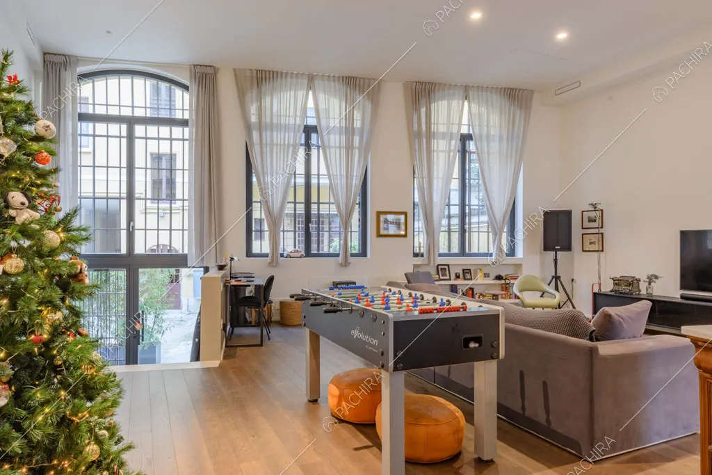 Zona living con pavimento in parquet, pareti bianche e finestre in stile industriale