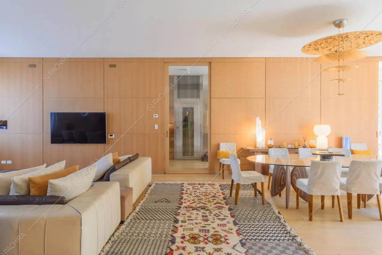 Divano angolare e tavolo da pranzo nella sala con parete in legno