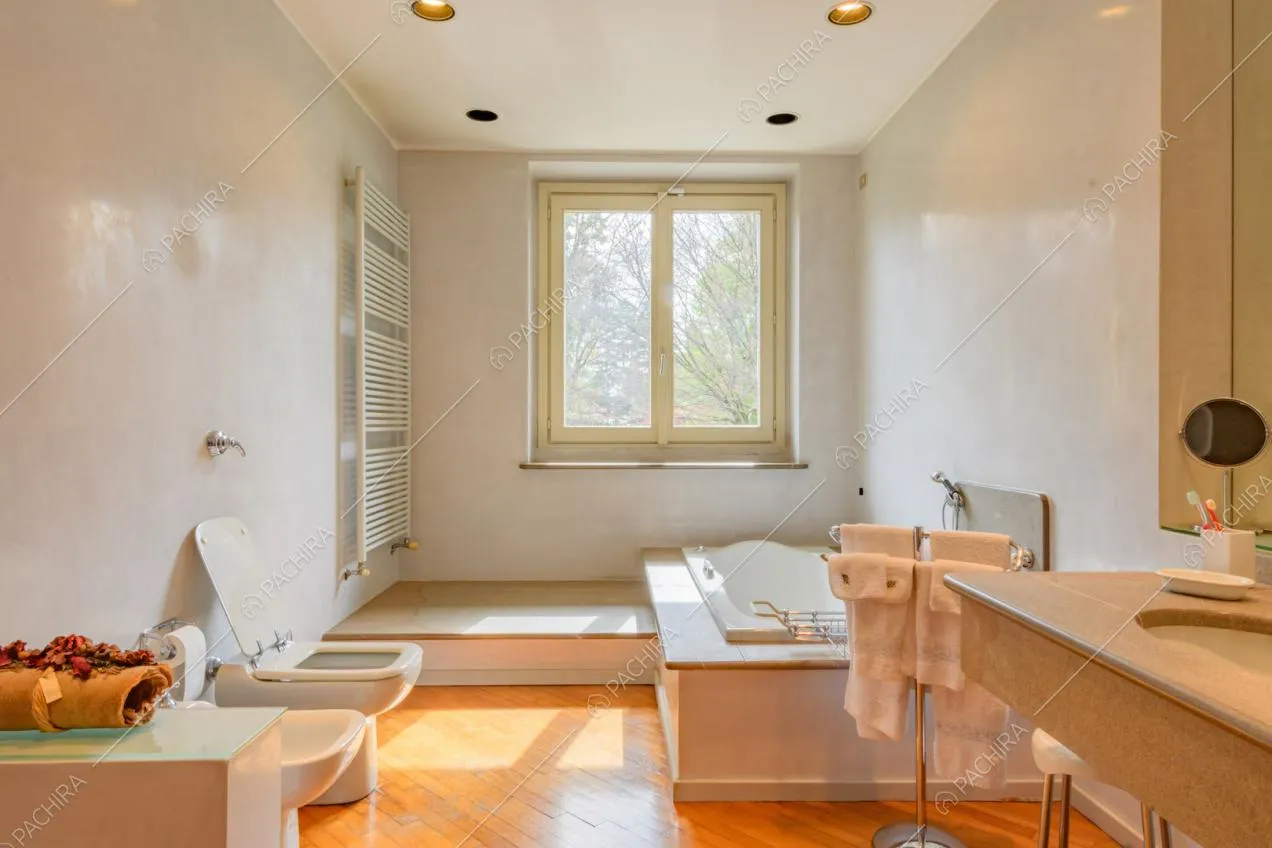 Grande bagno con pareti bianche, pavimento in parquet e vasca