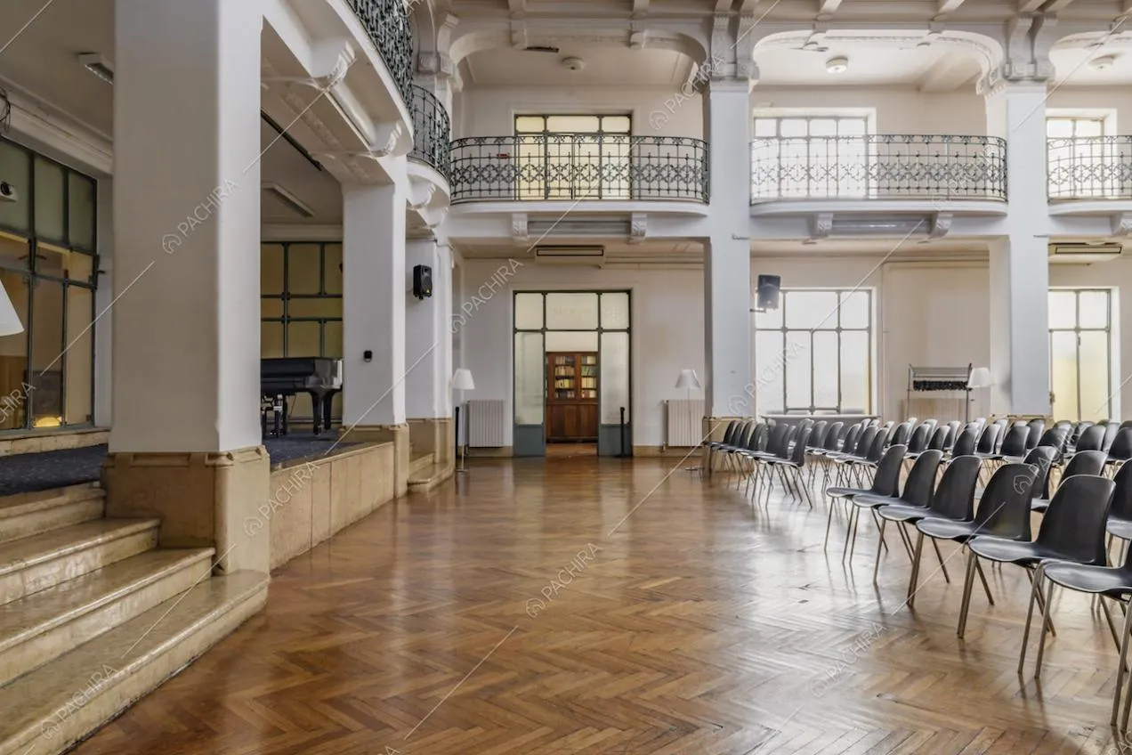 Ampio salone con palco, colonne bianche, pavimento in parquet e balconi con balaustra azzurra