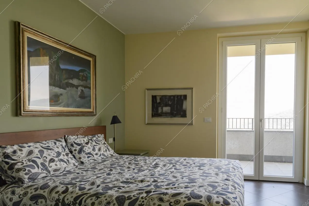 Camera da letto matrimoniale dalle pareti verde e gialla e accesso al balcone