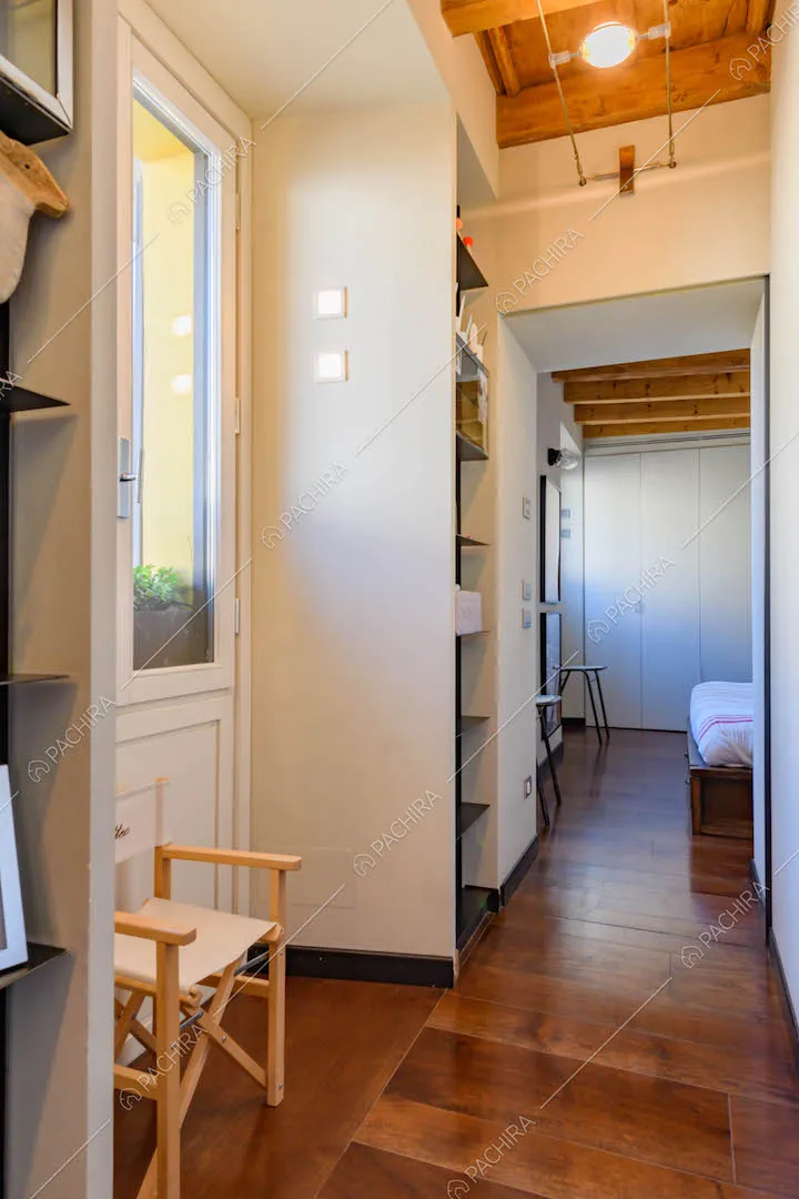 Corridoio con pavimento in parquet e pareti bianche conduce alla camera da letto