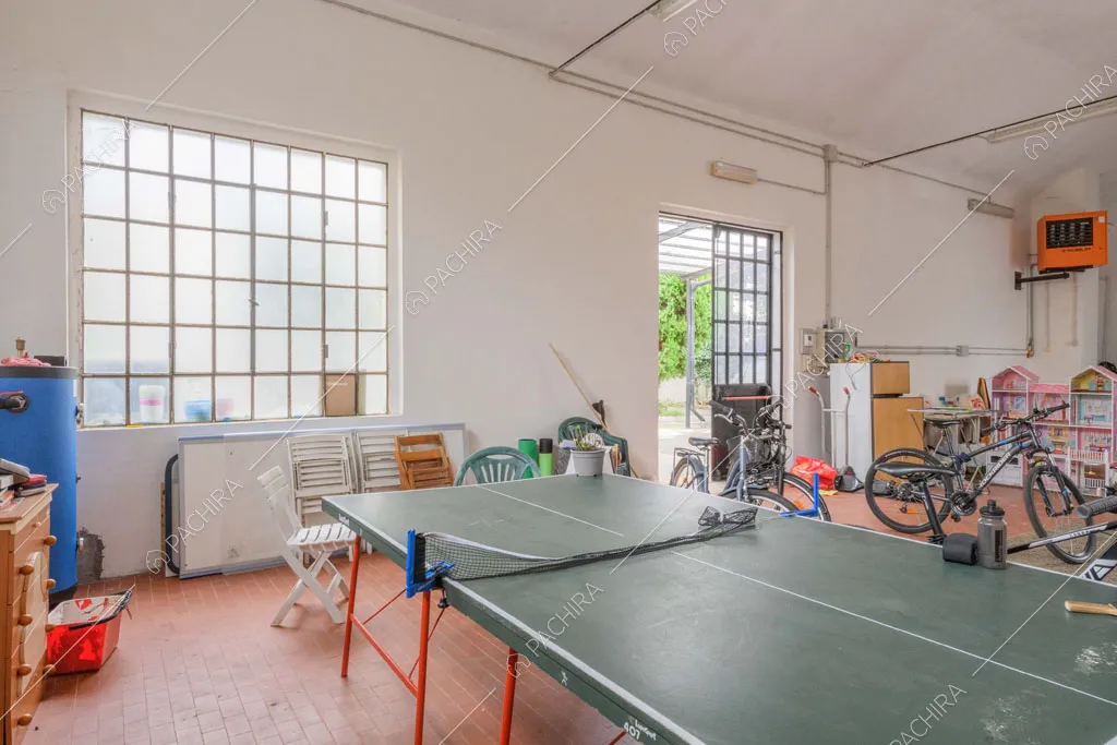 Tavolo da ping pong nel grande garage con vetrate industriali