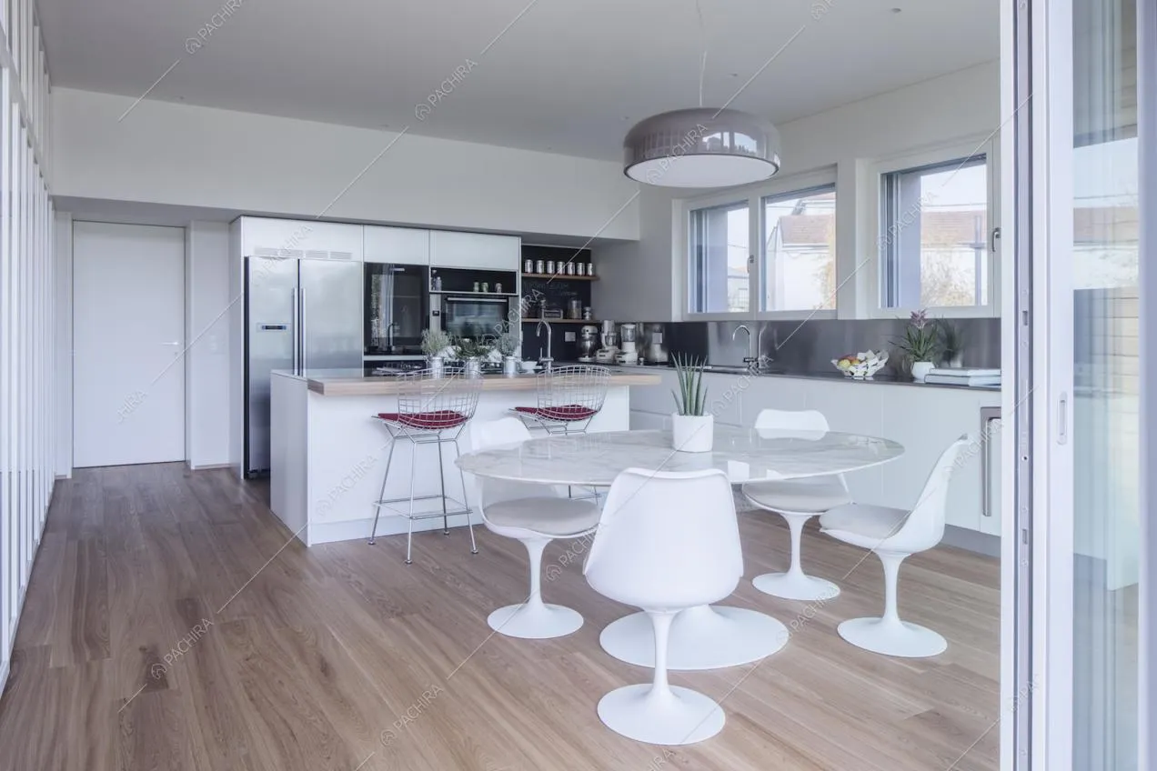 Cucina a isola con tavolo da pranzo in marmo, lampadario di design, pareti bianche e pavimento in parquet