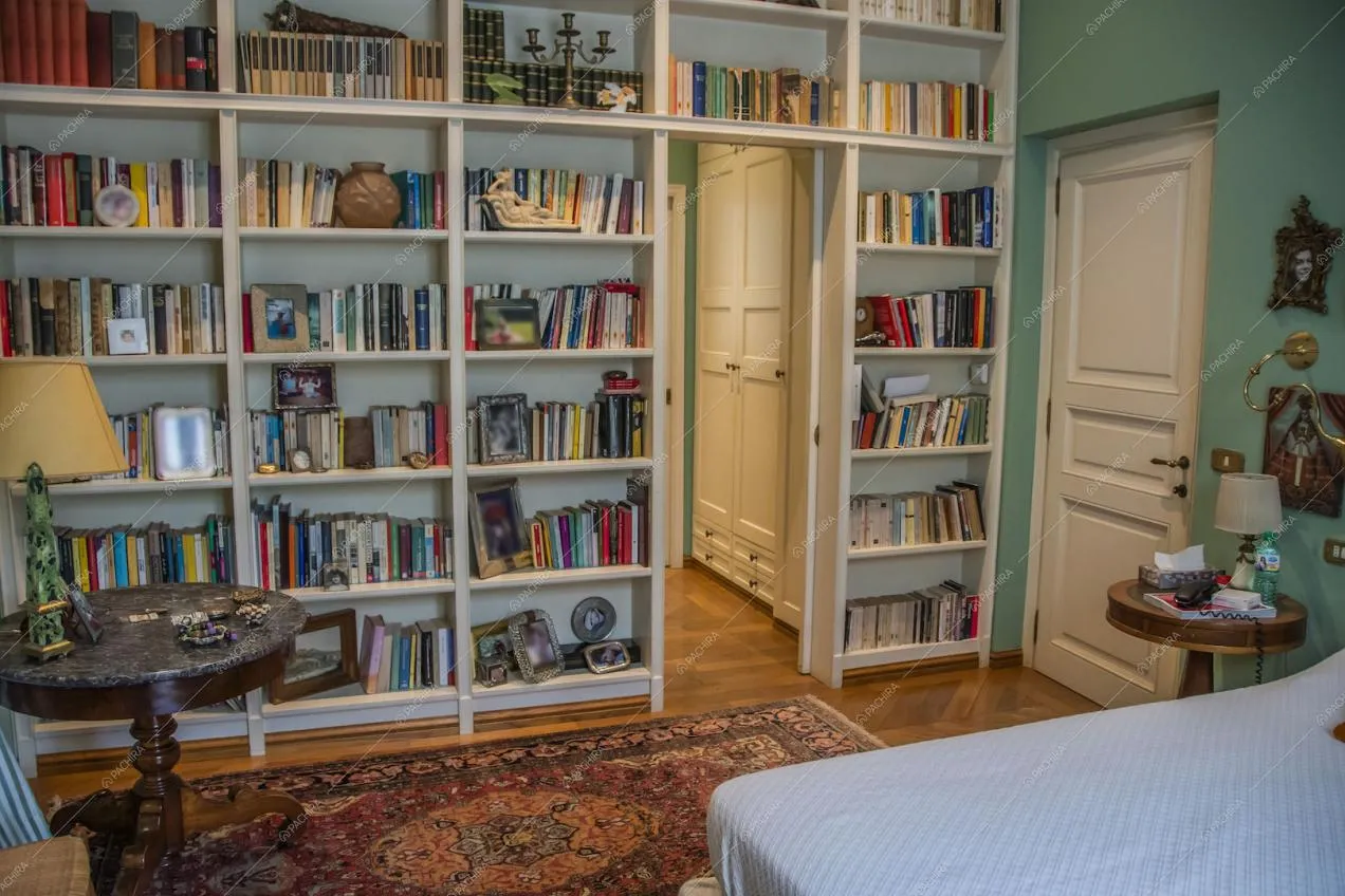 Grande libreria bianca a muro nella stanza da letto matrimoniale con pavimento in parquet