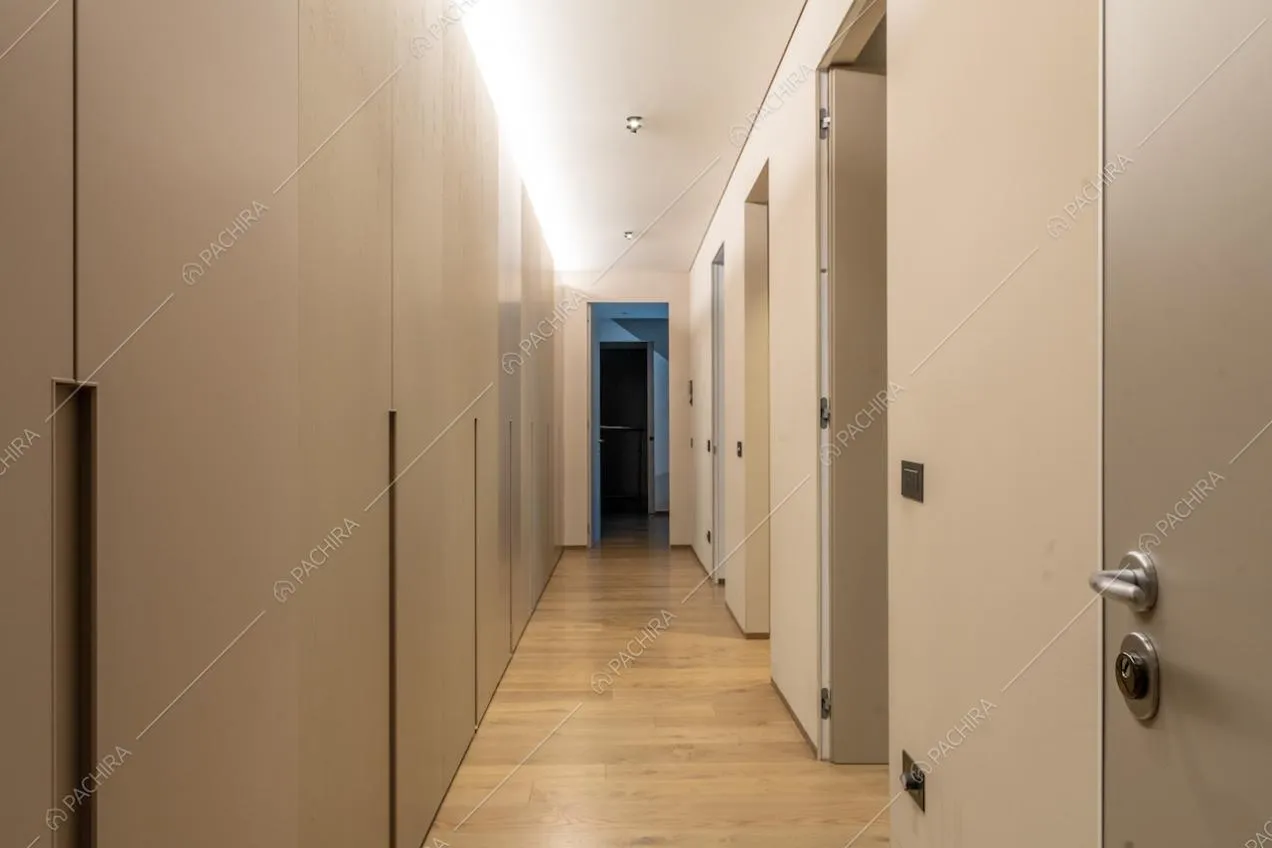 Lungo corridoio con pavimento in parquet e armadi a parete