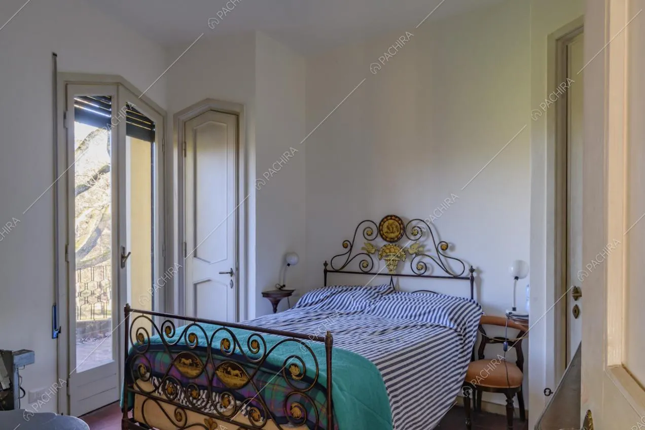 Camera da letto dalle pareti bianche e con accesso al balcone tramite porta-finestra