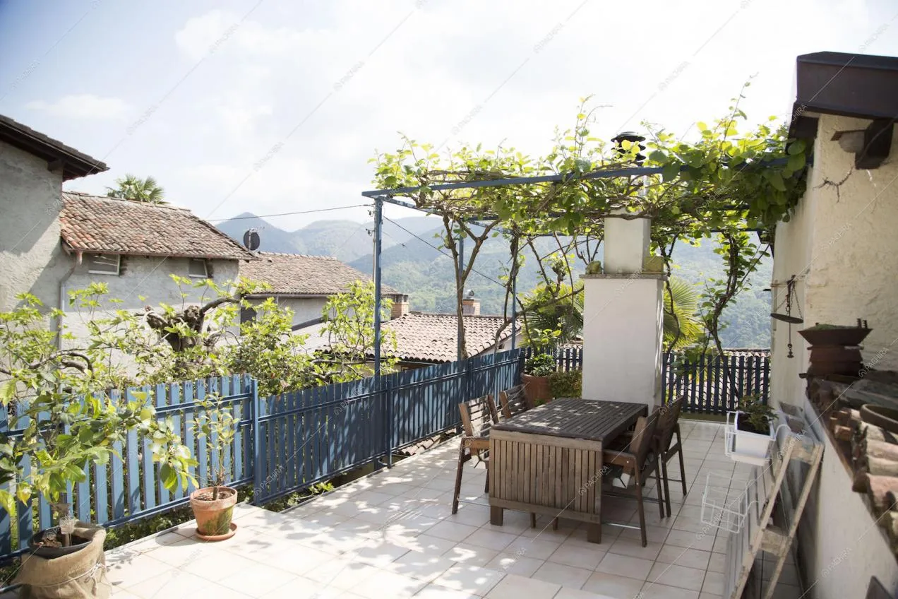 Terrazza con vista sulle montagne con veranda con rampicante e tavolo da pranzo in legno