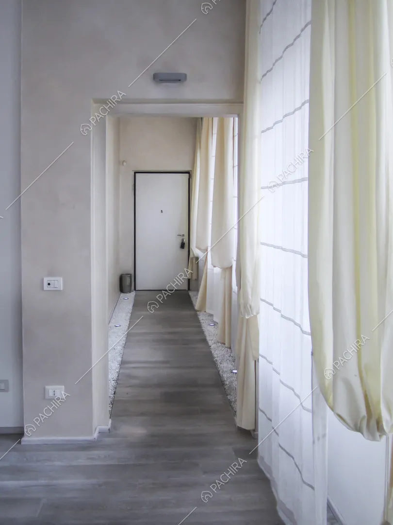 Porta d'ingresso e corridoio con ai lati sassolini e faretti