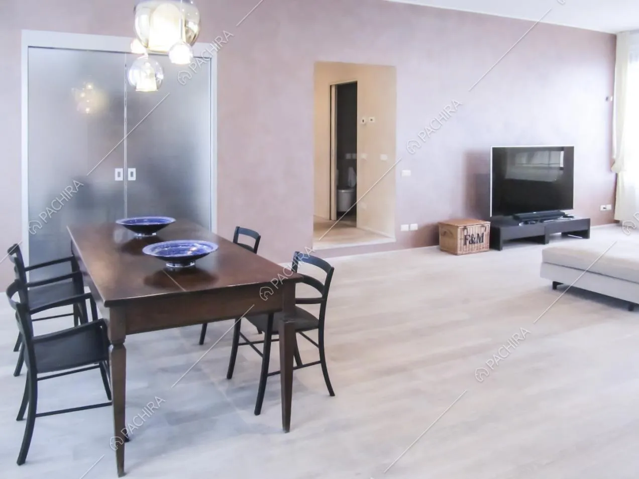 Zona pranzo e living con scorcio sul corridoio e porta doppia in vetro