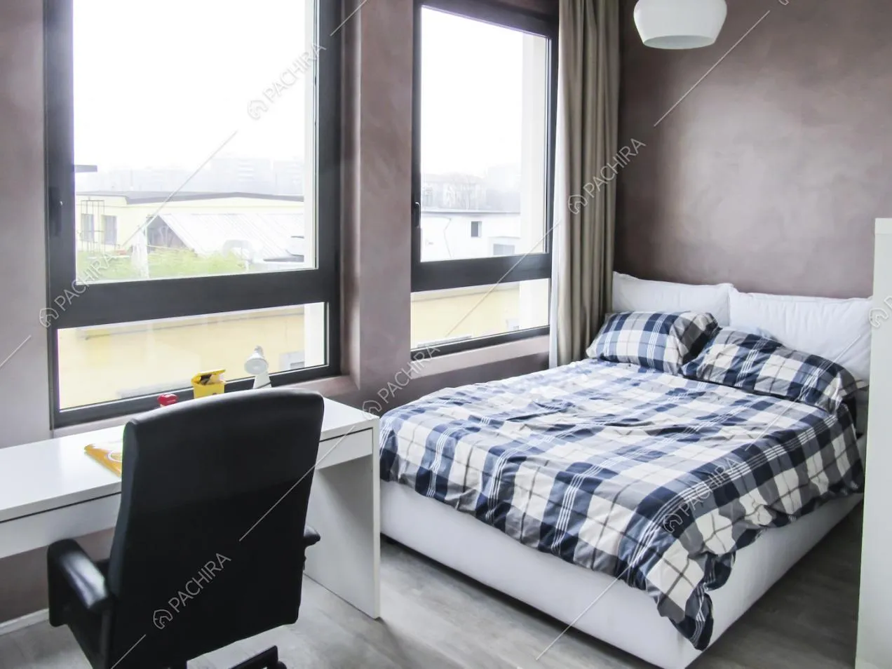 Camera da letto con scrivania, poltrona nera girevole e ampie vetrate