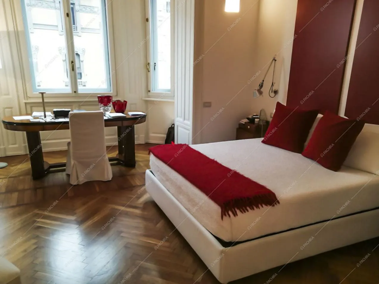 Pavimento in parquet a spina di pesce in camera da letto matrimoniale con scrivania e pareti bianche con boiserie