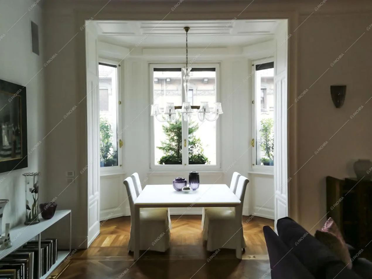 Sala da pranzo con pavimento in parquet a spina di pesce, pareti bianche con boiserie e tavolo bianco