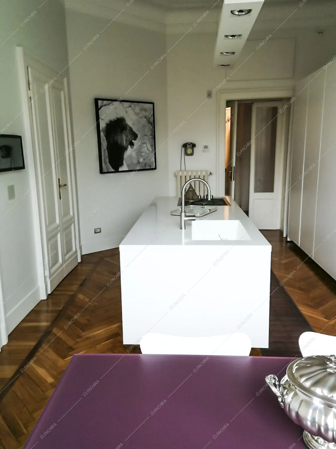 Cucina dalle pareti con boiserie, pavimento in parquet a spina di pesce e isola bianca con lavandino