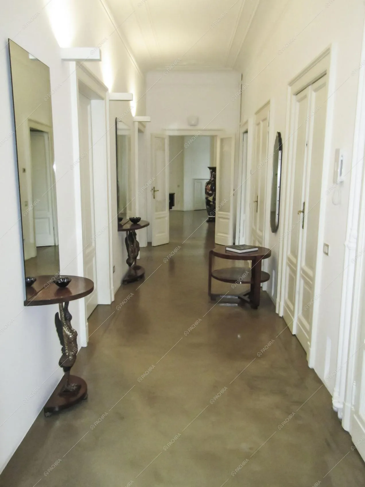 Ampio corridoio con soffitto bianco con boiserie e tavolini in legno