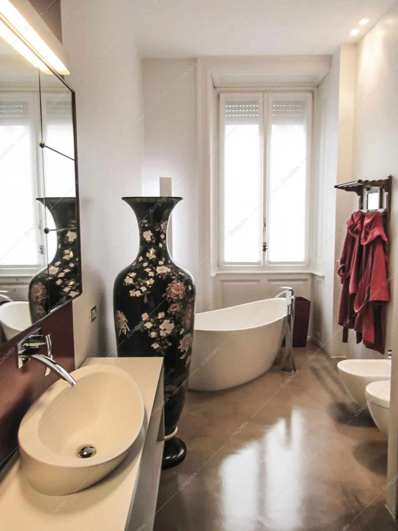 Bagno con pareti bianche, vasca di design e grande anfora decorata