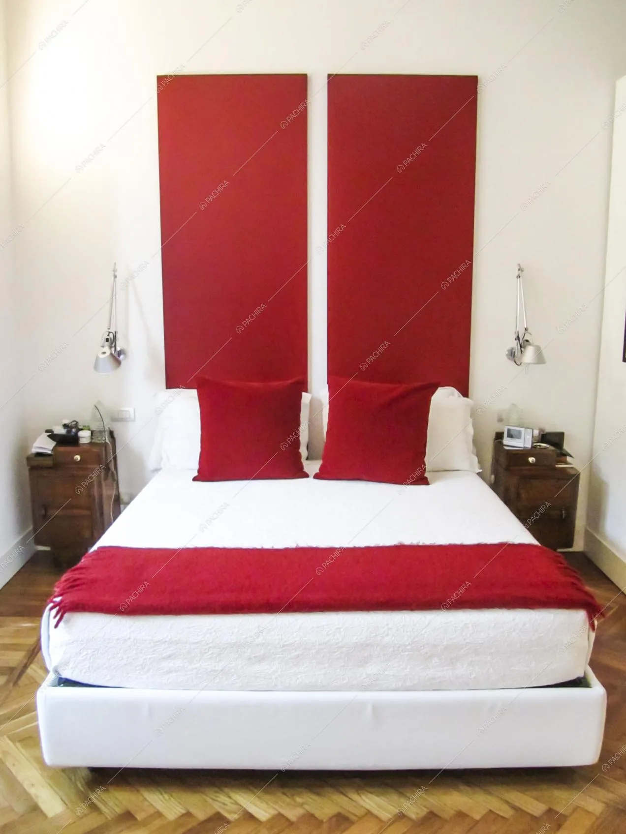 Letto matrimoniale bianco in luminosa camera con pavimento in parquet a spina di pesce