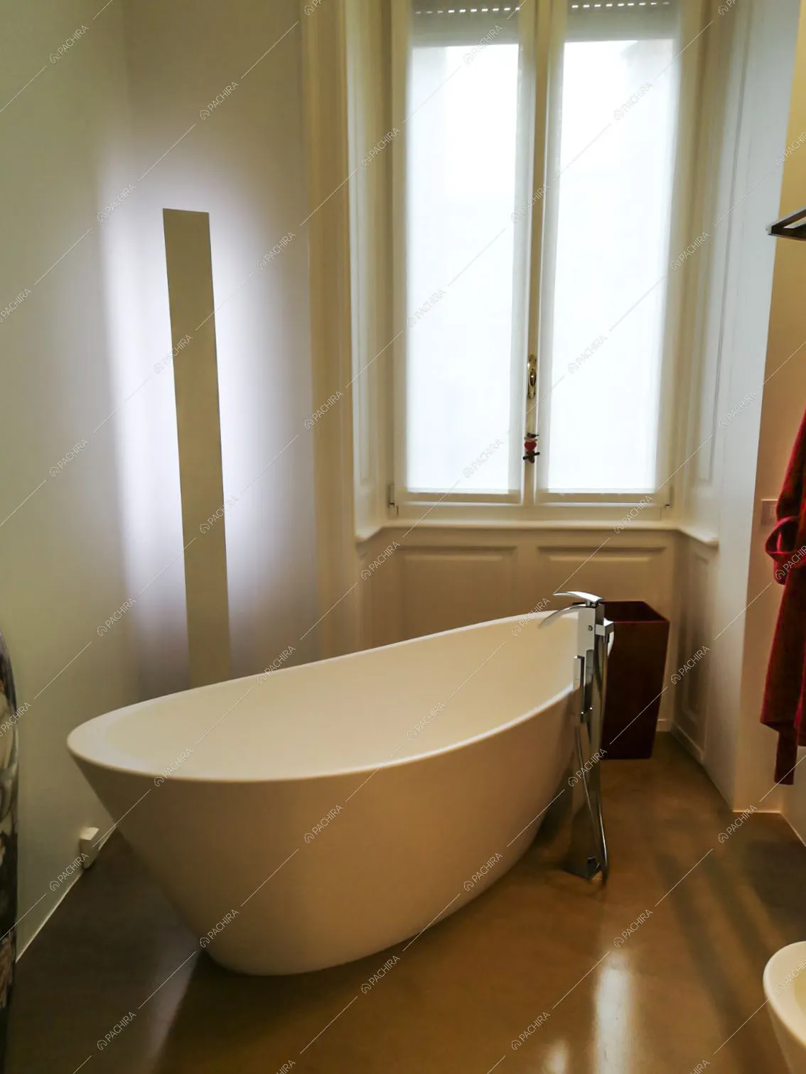Vasca di design nel bagno dalle pareti bianche e con pavimento in resina