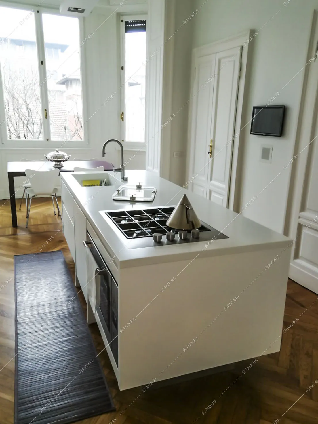 Isola bianca con lavandino e fornelli a gas nella cucina con pavimento in parquet